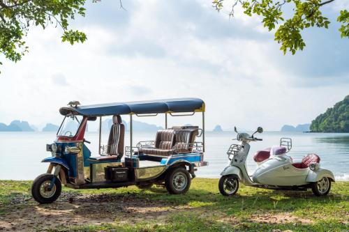 a golf cart and a scooter parked next to a lake at Six Senses Yao Noi in Ko Yao Noi