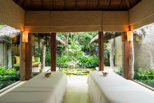 two beds in a room with a view of a garden at Six Senses Yao Noi in Ko Yao Noi