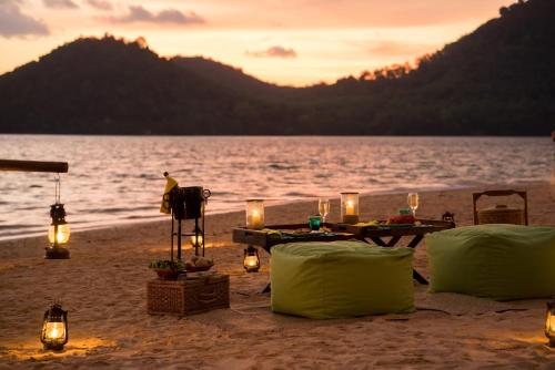 a table on the beach with candles and lights at Six Senses Yao Noi in Ko Yao Noi