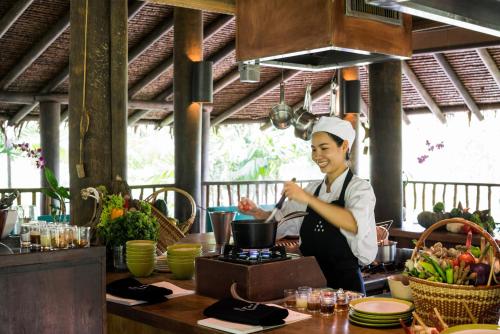 a woman standing in a kitchen preparing food at Six Senses Yao Noi in Ko Yao Noi