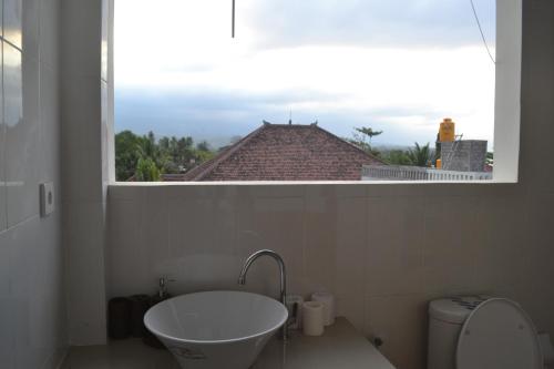 a bathroom with a window and a tub and a toilet at Master Homestay in Amed