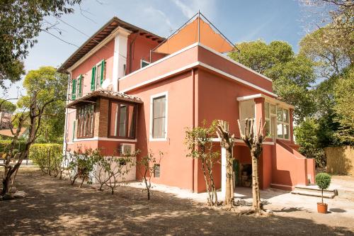 uma casa cor-de-rosa com árvores à frente. em B&B Villa Regina em Pisa