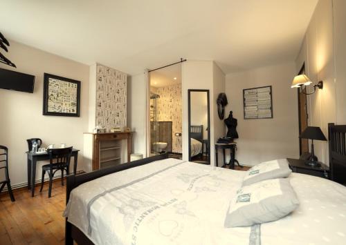 a bedroom with a large bed and a table and chairs at Aux Petits Bonheurs in La Gorgue
