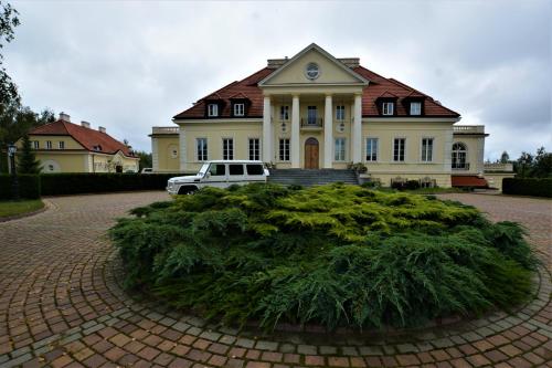 een wit busje geparkeerd voor een groot huis bij Dwor Osieczek in Pniewy
