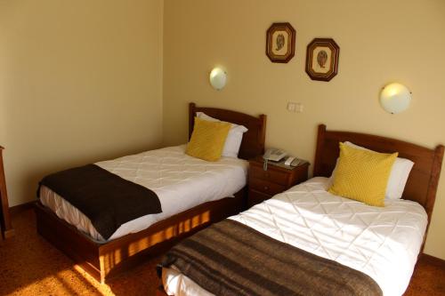 two beds in a hotel room with yellow pillows at A Muralha in Almeida
