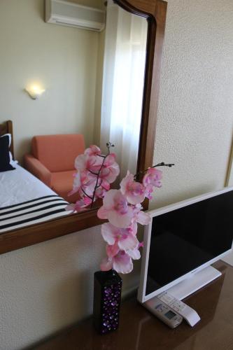 a vase with pink flowers on a desk next to a mirror at A Muralha in Almeida