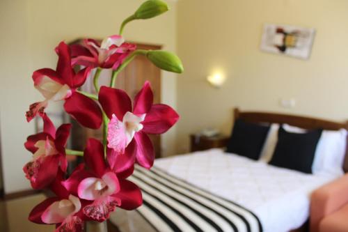 a vase filled with red flowers in a bedroom at A Muralha in Almeida