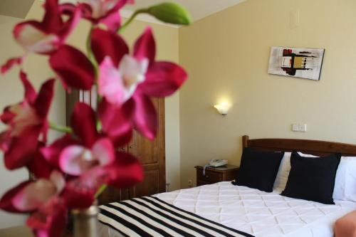 a bedroom with a bed with red flowers in a vase at A Muralha in Almeida