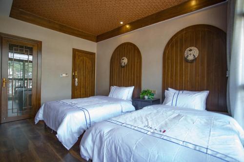 two beds sitting next to each other in a bedroom at Wang Jiang Reclusive Boutique Inn in Fenghuang