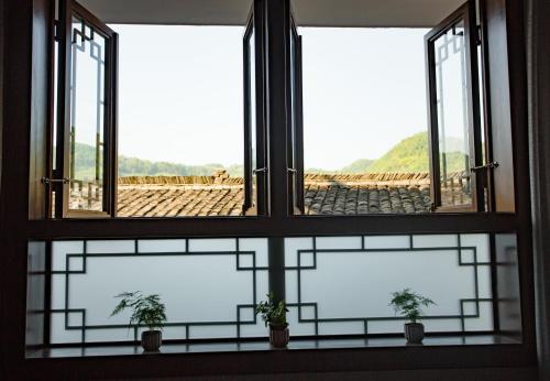 a window with three potted plants in front of it at Wang Jiang Reclusive Boutique Inn in Fenghuang