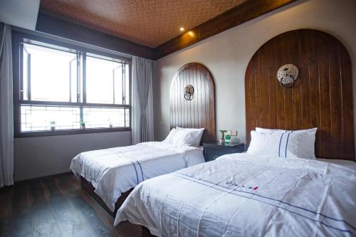 a hotel room with two beds and two windows at Wang Jiang Reclusive Boutique Inn in Fenghuang