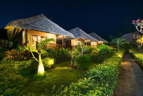 a resort with a row of huts at night at Laguna Reef Huts in Nusa Lembongan