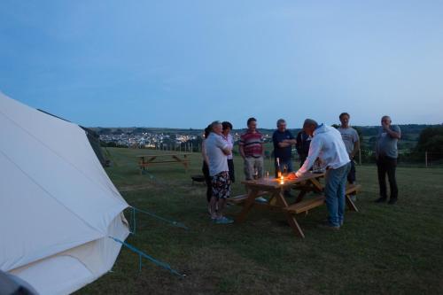 a group of people standing around a picnic table with a fire at Herston Caravan & Camping in Swanage