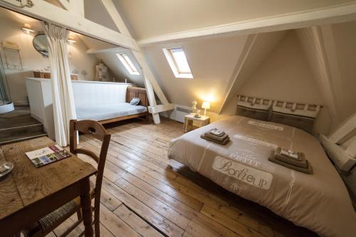 a bedroom with a king sized bed and a table at Aux Petits Bonheurs in La Gorgue