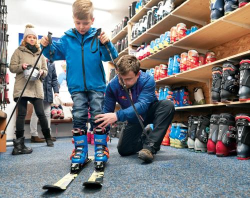 a man manipulating a young boy on skis in a store at Familotel Amiamo in Zell am See