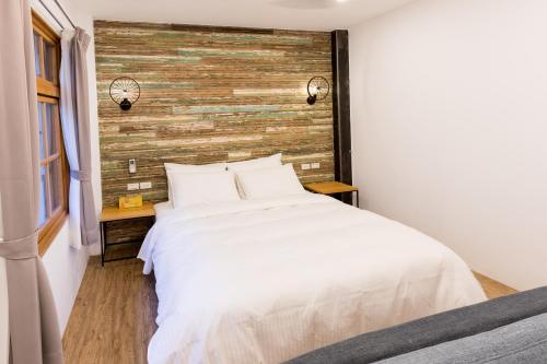 a bedroom with a white bed and a wooden wall at Atreeium in Tainan