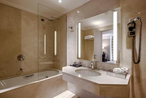 W łazience znajduje się umywalka, wanna i lustro. w obiekcie Ergife Palace Hotel w Rzymie