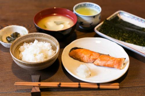 una mesa con un plato de comida con arroz y palillos chinos en Female-Only Guesthouse Tomari-ya en Tondabayashi