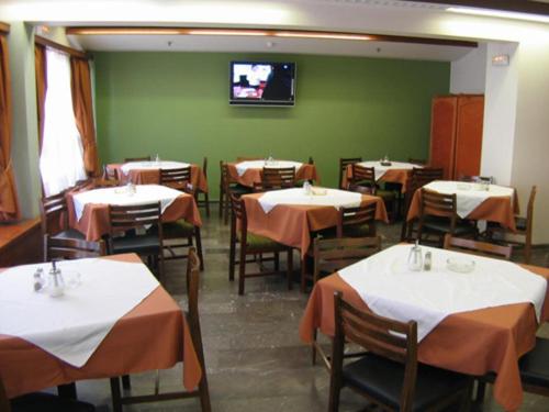 a restaurant with tables and a tv on a green wall at Diana Hotel in Chios