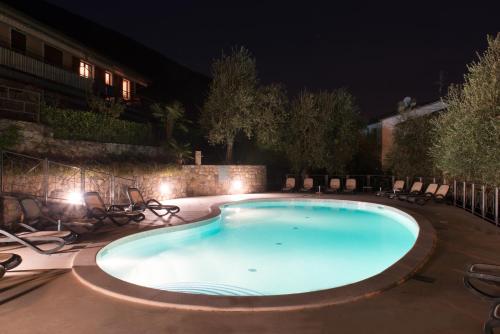 a swimming pool at night with chairs around it at Villa Due Leoni - Residence in Brenzone sul Garda