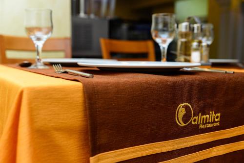 a table with a plate and wine glasses on it at Hotel Ildis in Iaşi