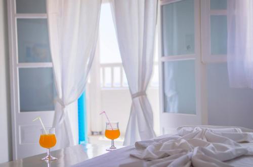dwie szklanki soku pomarańczowego siedzące na stole obok łóżka w obiekcie Limnionas Bay Village Hotel w mieście Marathokampos
