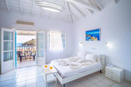 a white bedroom with a bed and a balcony at Limnionas Bay Village Hotel in Marathokampos