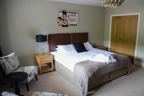 a bedroom with a bed with a chair and a table at The Gower Hotel in Swansea