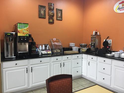 a kitchen with white cabinets and black counter tops at Super 8 by Wyndham Longview/North in Longview