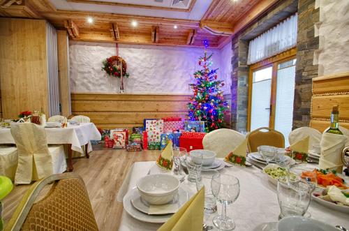 a dining room with a christmas tree in the background at Hotel Toporów in Białka Tatrzanska
