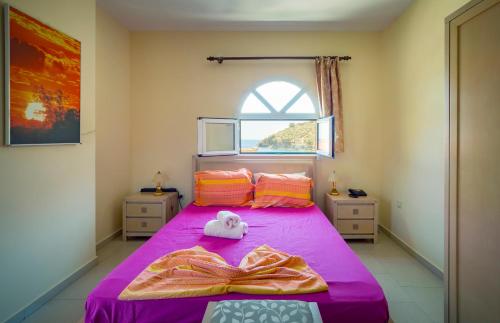 a bedroom with a pink bed with a stuffed animal on it at Limnionas Bay Village Hotel in Marathokampos