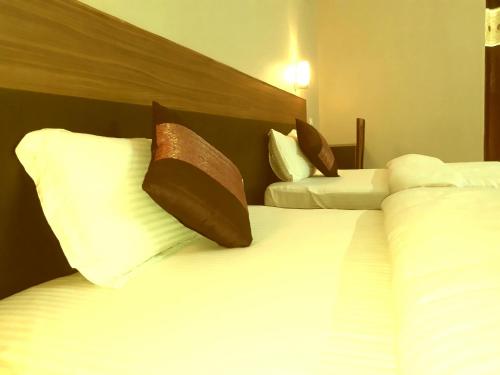 two beds in a hotel room with white sheets and pillows at Hotel Abhilasha in Giriak