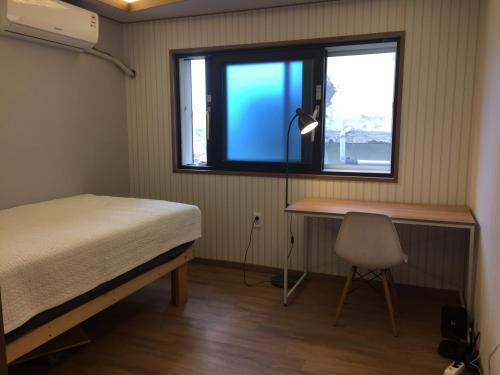 a bedroom with a bed and a desk and a window at Guest House Dalggume in Mokpo