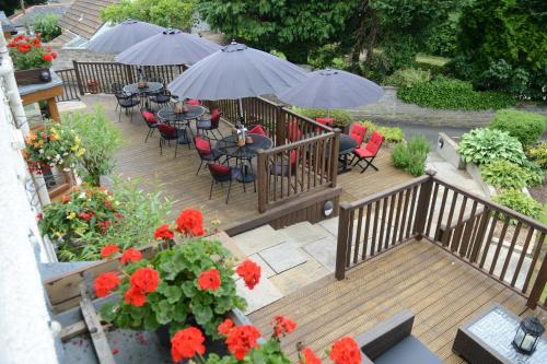 a wooden deck with chairs and tables and umbrellas at The Gower Hotel in Swansea