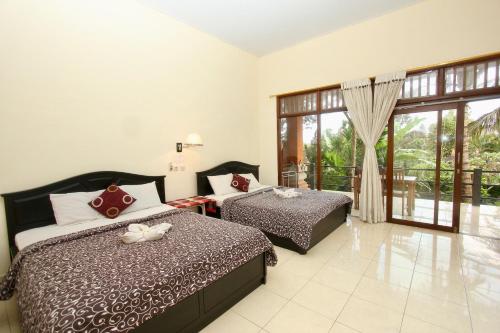 a bedroom with two beds and a balcony at Rahayu House Ubud in Ubud