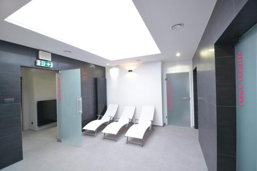 a waiting room with white chairs and a tv at Hotel Tychy Prime in Tychy