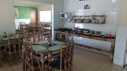 a dining room with tables and chairs and a kitchen at Hotel Maringa in Maringá