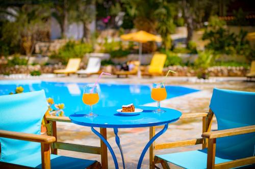 a table with two glasses of orange juice and a piece of cake at Limnionas Bay Village Hotel in Marathokampos