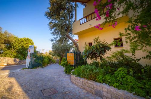 a yellow building with a fence next to a street at Limnionas Bay Village Hotel in Marathokampos