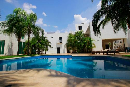 a swimming pool in front of a house with palm trees at Hotel Embajadores in Mérida