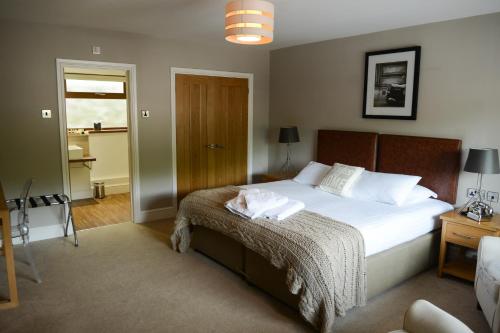 a bedroom with a bed with white sheets and a table at The Gower Hotel in Swansea
