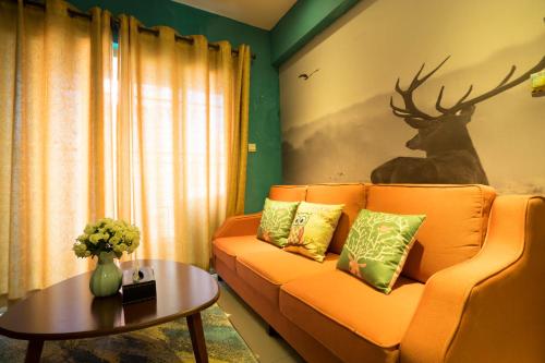 a living room with an orange couch and a deer mural at YuMi Gaopai in Guangzhou