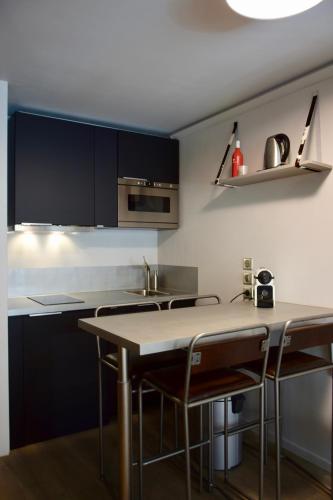 une cuisine avec des armoires noires, une table et des chaises dans l'établissement Little Suite Val d'Isère, à Val dʼIsère