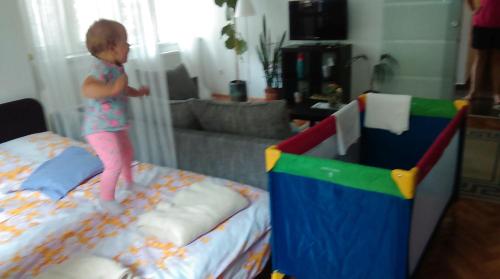a little girl standing on top of a bed at Belvárosi Studio Apartman in Győr