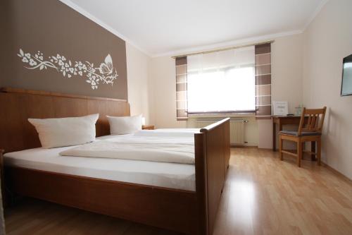a bedroom with a bed and a desk and a window at Gasthaus Pension Geimer in Plütscheid