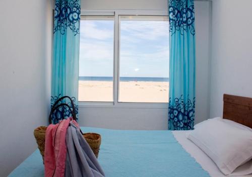 a bedroom with a bed and a window with a beach at Apartamentos Calypso in Punta Umbría