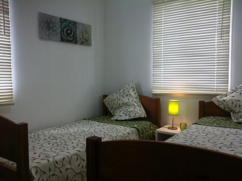 um quarto com 2 camas, um candeeiro e janelas em A Casa Da Avenida em Madalena