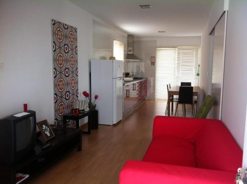 a living room with a red couch and a kitchen at A Casa Da Avenida in Madalena