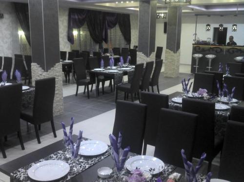un comedor con mesas y sillas negras y flores púrpuras en Best Hotel, en Hunedoara