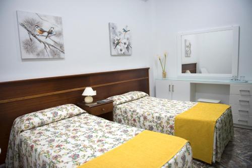 プエルト・デ・ラ・クルスにあるPension Los Geraniosのベッド2台と鏡が備わるホテルルームです。